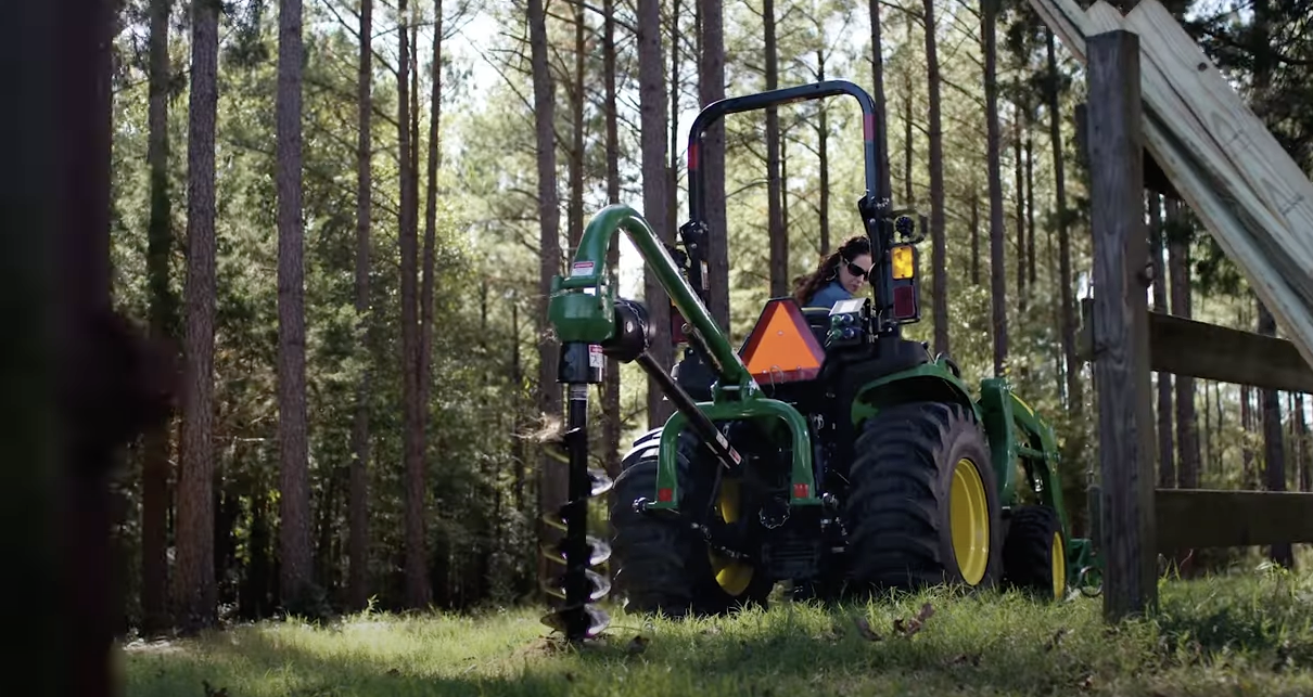 A woman utilizing the John Deere 3038E on a wooded property.